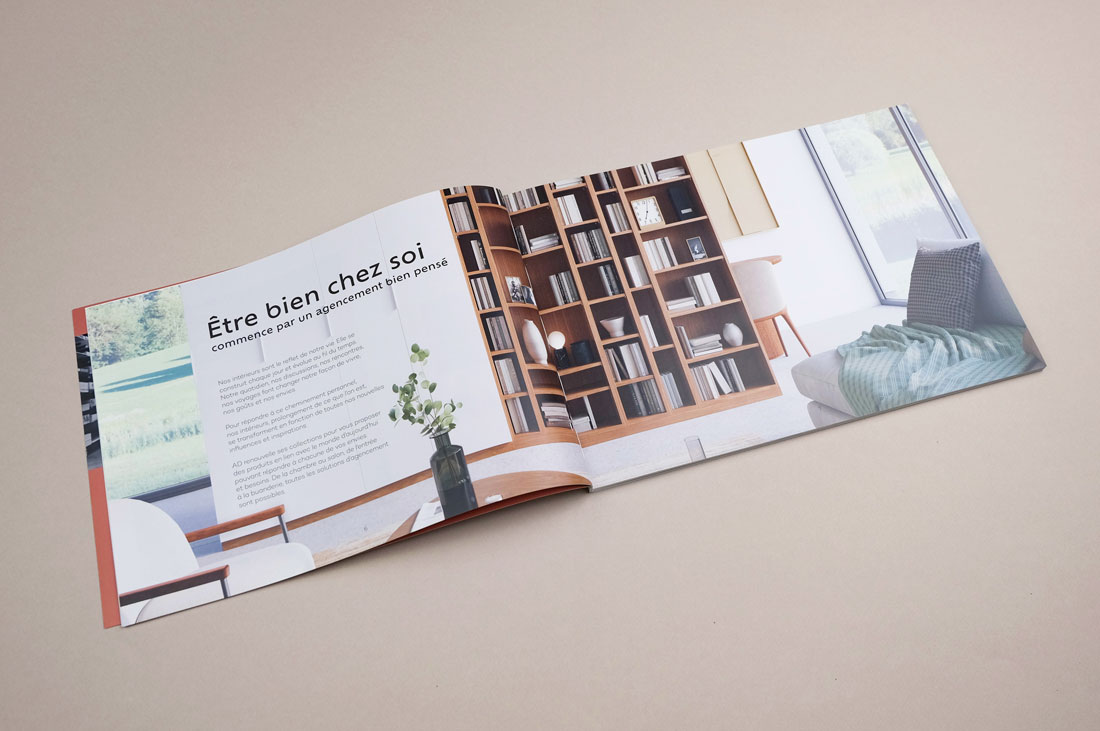 Pages intérieures du catalogue AD 2023. Représente la bibliothèque d'un salon. Légende 